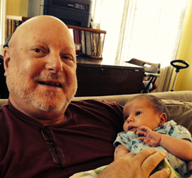 Man holding a baby on a couch.