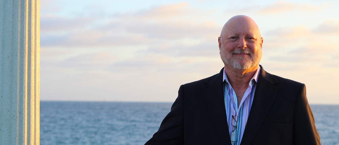 A man in a suit standing next to the ocean.